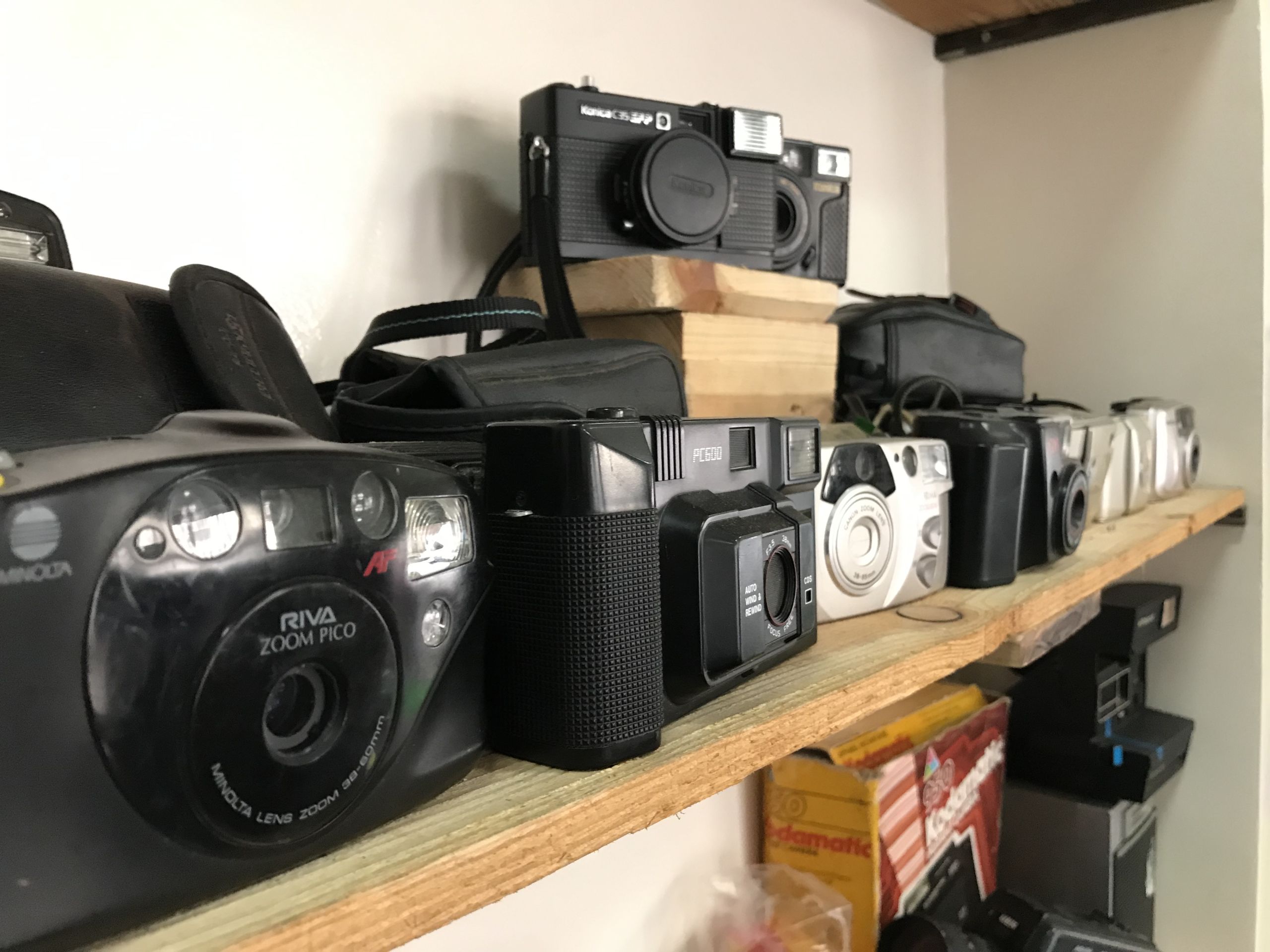 A shelf stacked with old cameras from the 2000s.